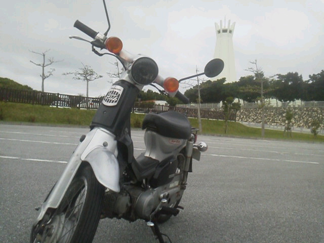 平和祈念公園の塔を背景に停車した原付バイク(ゴール地の風景)