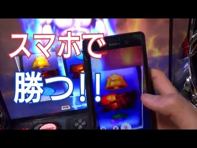 スロット実機の液晶とスマートフォン画面を並べ「スマホで勝つ!!」の文字(動画「ガックン 見抜く方法 7揃いのパチンコ屋 攻略」より)