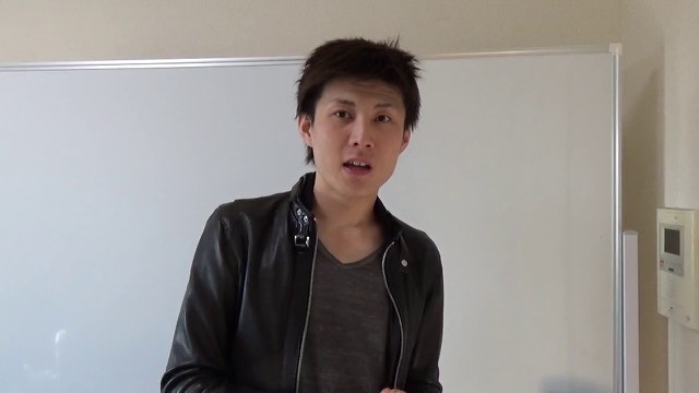 ホワイトボード前で革ジャン姿の本人が正面を向き話す(動画「夏目の立ち回りを公開します【パチスロ】【スロット】」より)