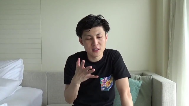 ソファに座り手振りする本人(ホテル室内)(動画「【簡単】毎日、ある1つの事をするだけで人生が変わる話」より)