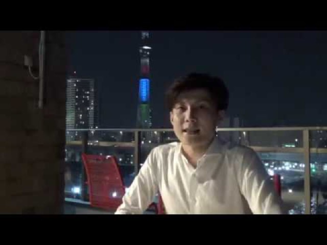 夜景(スカイツリー)を背にしたバルコニーの本人(動画「【単純】一人勝ちできる考え方」より)