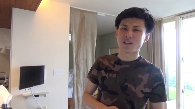 迷彩シャツ姿で明るい室内に立つ本人(動画「【人生終了】おじいちゃんになって後悔しそうな人」より)