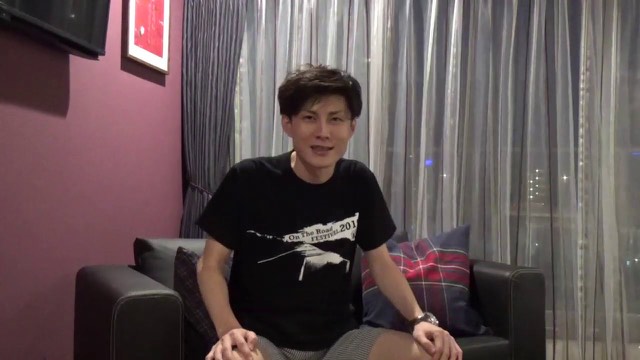 黒Tシャツ姿でソファに座る本人(夜景背景)(動画「【社畜必見】最近、僕がスロットを打ってない理由」より)