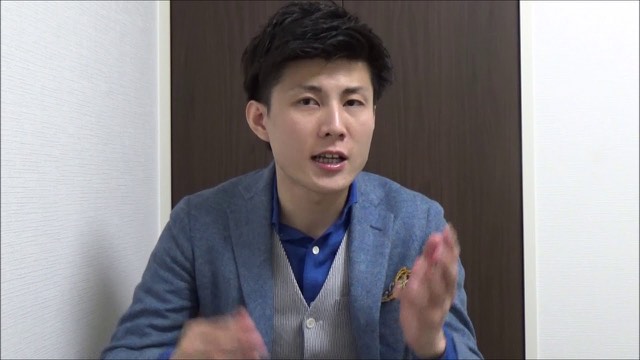 ベスト・ジャケット姿で身振りする本人(動画「ネットビジネスで成功するコツ サラリーマンを辞めたい」より)
