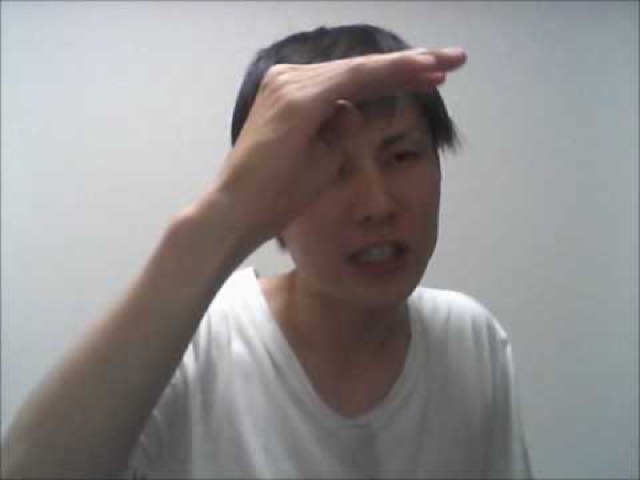 白Tシャツで額に手をかざす本人(動画「伝説のスーパーサイヤ人になってもらいます【パチスロ】」より)