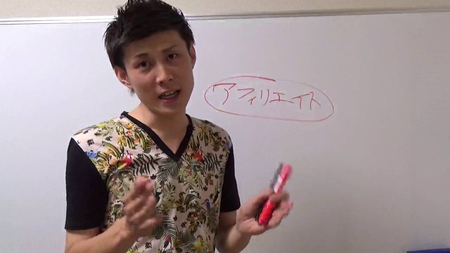 「アフィリエイト」と板書したボード前で赤ペンを持つ本人(動画「無料パチスロサイト、ブログが稼げる理由【パチスロ】…」より)