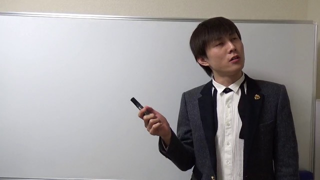 マーカーで指し示しながら話すリボンタイ姿の本人(動画「激アツイベントを見抜く方法【パチスロ】【スロット】」より)