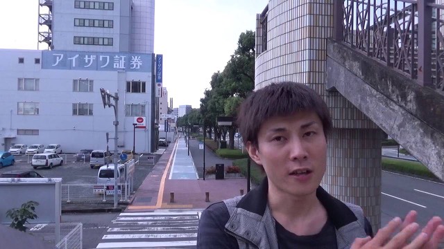 証券会社ビルの並ぶ路上を背景に話す本人のアップ(動画「GOGOジャグラーで勝てない理由【パチスロ】…」より)