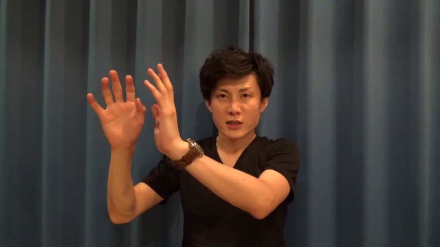 両手を挙げて話す本人(動画「チャンスの神様は前髪しかない」より)