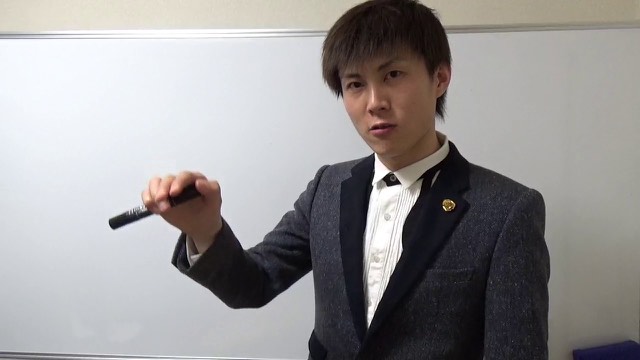 ホワイトボードの前でマーカーを持ち指し示すところ