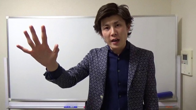 ホワイトボード前で片手を挙げる本人「月収30〜60万のスロプロから抜け出すには」